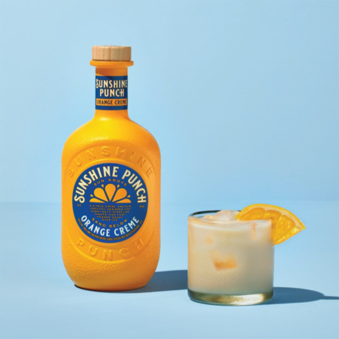 Bottle of Sunshine Punch Orange Creme with a glass of the drink on a blue background