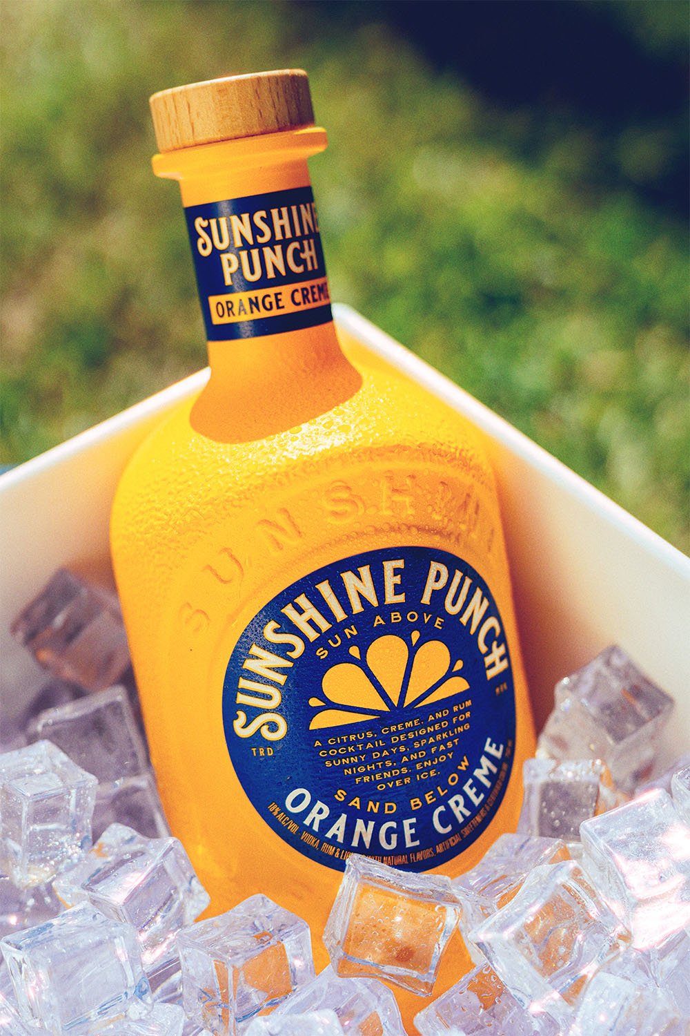 Sunshine Punch Orange Creme bottle on ice with grass background